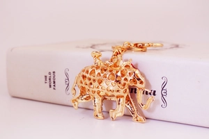 Close-up of golden elephant keychain with heart hollow-out design on a white book
