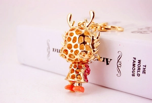 Close-up of golden hollow metal dragon keychain with sparkling pink rhinestones