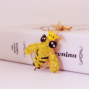 Portachiavi ape dorata con strass gialli e corona posizionato su un libro bianco