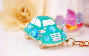 Détail d'un porte-clés voiture vert menthe avec strass bleus et finitions dorées