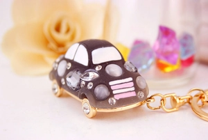 Gros plan d'un porte-clés de voiture serti de strass avec fermoir doré sur fond floral