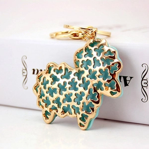 Detail view of gold sheep keychain with tiffany blue floral cutouts on white books