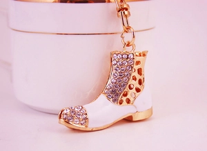 Close-up of golden high heel boot keychain with white enamel and sparkling rhinestones