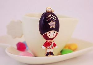 Close-up of royal guard keychain with enamel detail and rhinestones on a ceramic cup edge