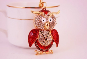 Close-up of golden owl keychain featuring red enamel wings and sparkling rhinestones