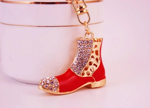 Macro shot of red enamel boot keychain with rhinestones and gold-plated metal link