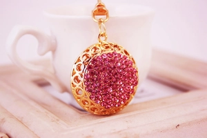 Gros plan détaillé du porte-clés doré orné de strass roses et motifs évidés
