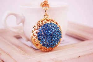 Gros plan d'un porte-clés doré en métal creux avec des strass bleu foncé sur bois