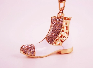 Macro shot of gold-plated boot keychain featuring white enamel and rhinestone inlay