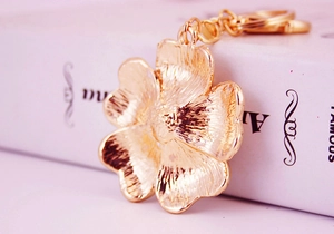 Detailed macro view of a gold-plated flower keychain with intricate embossed metal texture