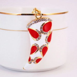 Vue macro d'un pendentif cor en émail blanc avec cristaux rouges sur base dorée