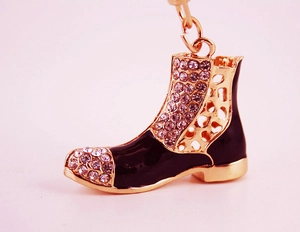 Macro detail of boot keychain featuring black enamel, crystals, and gold metal base