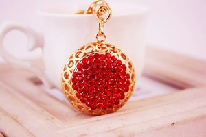 Détail d'un porte-clés boule de cristal à strass rouges avec base dorée ajourée