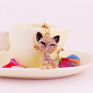 Cute gold fox keychain with white rhinestones hanging on a stylish coffee cup