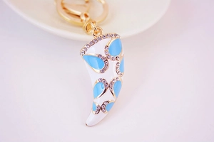 Détail macro du porte-clés en forme de cor avec motif à l'huile bleue et strass brillants