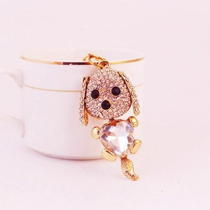Porte-clés chiot doré avec cœur en cristal et strass sur une tasse à café dorée