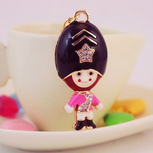 Royal Guard soldier keychain with rhinestone accents on a cream coffee cup
