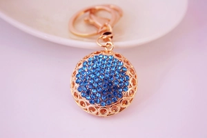 Gros plan d'un porte-clés en alliage doré orné d'une sphère aux strass bleus brillants