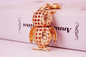 Detail of owl keychain featuring golden hollow clover pattern and branch base