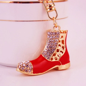 Red boot keychain with rhinestones and gold-plated metal frame on a ceramic base