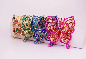 Detail showing four crystal butterfly hair clips in gold, green, blue, and red colors