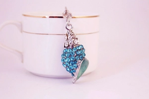 Macro detail of conch shell keychain with sky blue rhinestones and light green enamel