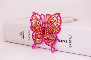 Detail of golden butterfly keychain with red rhinestones and vintage filigree design