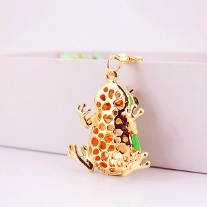 Cute golden frog keychain with green enamel detail and crystal accents on a display box