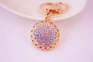 Détail macro du porte-clés sphère en strass violet étincelant avec motif évidé or rose