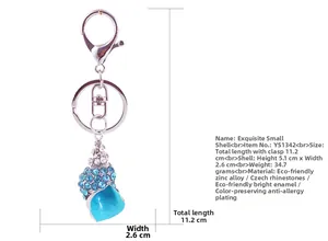 Macro detail of blue conch keychain with crystals and dimensions on a white background