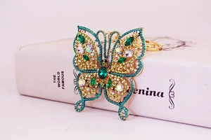 Macro shot of butterfly keychain with green gemstones and sparkling crystals