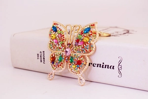 Macro detail of colorful butterfly keychain with rhinestones and faux pearls on gold base