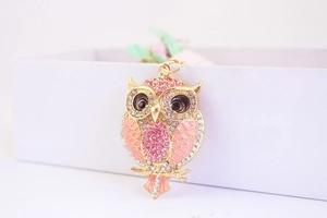 Détail du porte-clés hibou avec strass roses et émail corail sur métal doré brillant