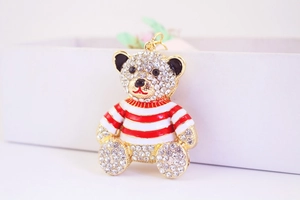 Dettaglio del ciondolo a forma di orso con strass bianchi e smalto a righe rosse