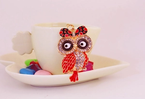 Détail du porte-clés hibou avec émail rouge, cristaux brillants et nœud à pois mignon