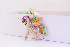 Gros plan détaillé d'un porte-clés licorne dorée avec ailes en émail et strass brillants