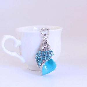 Blue rhinestone conch shell keychain pendant hanging on white ceramic cup holder