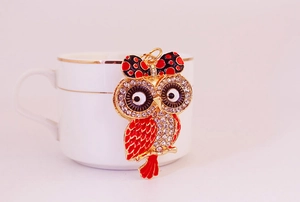 Détail du porte-clés chouette avec émail rouge et cristaux sur une tasse en céramique