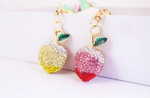 Close-up of sparkling rhinestone peach and apple keychains with gold alloy rings
