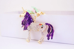 Macro view of crystal unicorn keychain with purple glitter mane and gold alloy base