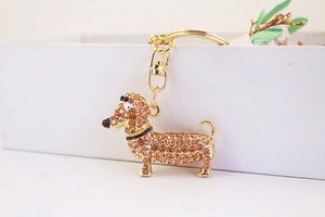 Détail du porte-clés teckel avec strass ambrés sur une boîte cadeau blanche