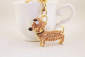 Gros plan d'un porte-clés teckel doré orné de strass ambrés sur une tasse blanche