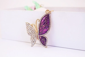 Vista detallada de un colgante de mariposa dorado con esmalte morado y diamantes