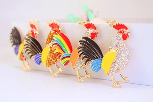 Vue détaillée de quatre pendentifs coq en strass colorés avec finitions en émail