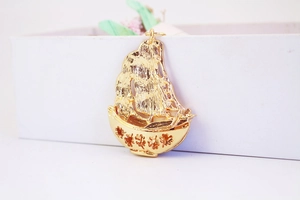 Détail d'un porte-clés voilier doré avec calligraphie chinoise sur une boîte cadeau