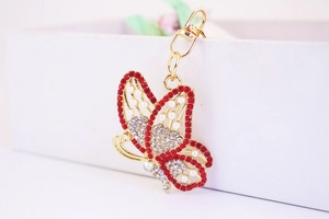 Detail of butterfly keychain with red and white rhinestones and pearls on gold metal
