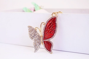 Primer plano de un llavero de mariposa con esmalte rojo y pedrería de cristal brillante