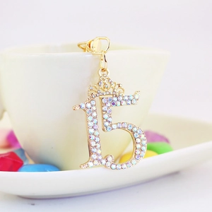 Porte-clés couronne numéro 15 avec strass colorés accroché à une tasse à café blanche