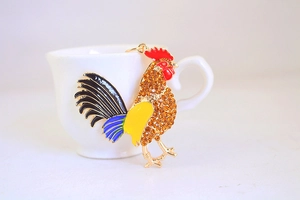 Macro détaillée d'un porte-clés coq en strass avec émail coloré et finition plaquée or