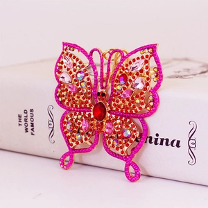 Elegant gold butterfly keychain with red rhinestones resting on a white book cover